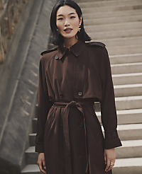 A woman wearing a brown belted trench coat stands in the foreground against a background of concrete stairs. carousel Product Image 4