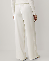 A person wears wide-leg white trousers and a white sweater against a plain, light-colored background. carousel Product Image 3