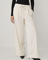 A person wearing a black top and wide-leg cream trousers stands against a plain white background. carousel Product Image 2