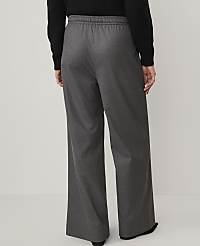 A person wearing a black top and wide-leg grey trousers stands against a plain, light-colored background. carousel Product Image 2