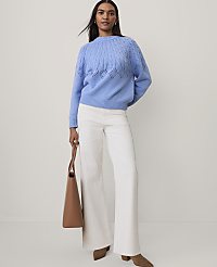 A woman wearing a blue knit sweater, white wide-leg pants, and brown shoes stands against a plain light gray background. carousel Product Image 3