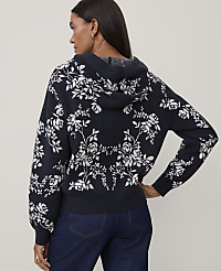 A woman wearing a navy blue floral hooded sweater and dark blue jeans stands against a plain light gray background. carousel Product Image 2