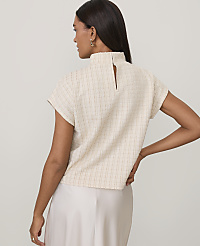 A woman wearing a cream-colored textured top and a white satin skirt stands against a plain light gray background. carousel Product Image 2