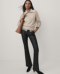 A woman wearing a beige cable-knit zip-up sweater, a checkered shirt, and black flared trousers stands against a plain white background. carousel Product Image 3