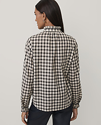 A woman wearing a black and white checkered shirt and dark trousers stands against a plain light gray background. carousel Product Image 2