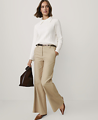 A woman wearing a white cable-knit sweater, tan flared trousers, and brown shoes stands against a plain light gray background. carousel Product Image 3