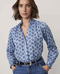A woman wearing a blue floral print blouse and blue jeans stands against a plain, light-colored background. carousel Product Image 1