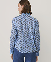 A woman wearing a blue patterned blouse and denim jeans stands against a plain, light-colored background. carousel Product Image 2