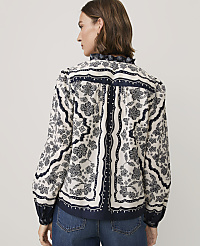 A woman wearing a floral patterned blouse and blue jeans stands against a plain light grey background. carousel Product Image 2