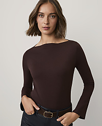 A woman wearing a dark brown long-sleeved top and black trousers stands against a plain, light-colored background. carousel Product Image 1