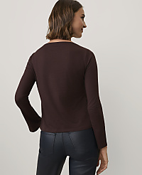 A woman wearing a dark brown long-sleeved top and black leather-look pants stands against a plain light gray background. carousel Product Image 2