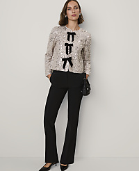 A woman wearing a sequined jacket with black bow accents and black trousers stands against a plain, light-colored background. carousel Product Image 2