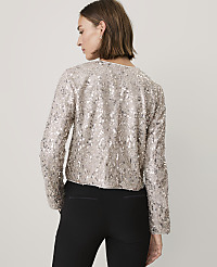 A woman wearing a shimmering silver sequined jacket and black trousers stands against a plain light gray background. carousel Product Image 3