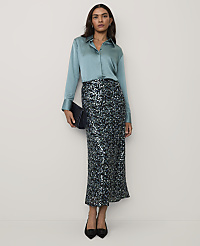 A woman wearing a light blue satin shirt and a sequined maxi skirt stands against a plain, neutral background. carousel Product Image 4