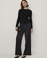 A woman wearing a black cardigan and wide-leg satin trousers stands against a plain white background. carousel Product Image 3