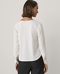 A woman wearing a white long-sleeved blouse and dark trousers stands with her back to the camera against a plain light gray background. carousel Product Image 2