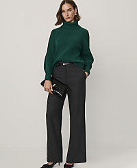 A woman wearing a green turtleneck sweater and grey wide-leg trousers stands against a plain white background. carousel Product Image 3