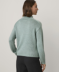 A woman wearing a light green knit sweater and dark trousers stands against a plain light gray background. carousel Product Image 2