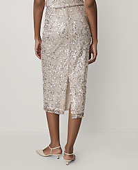 A person wears a shimmering gold sequined midi skirt and beige heels against a plain, light-colored background. carousel Product Image 3