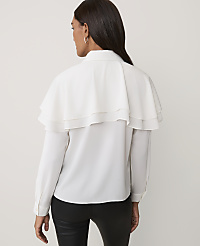A woman wearing a white ruffled blouse and black pants stands against a plain light-colored background. carousel Product Image 2