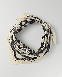 A cream-colored scarf with a black floral pattern is tied in a knot against a plain light gray background. carousel Product Image 1