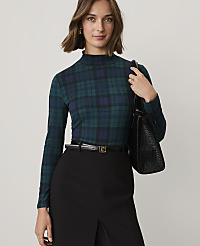 A woman wearing a green plaid turtleneck and black skirt stands against a plain light gray background. carousel Product Image 1
