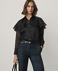 A woman wearing a black ruffled blouse and green plaid trousers stands against a plain light gray background. carousel Product Image 1
