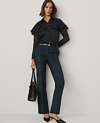A woman wearing a black ruffled blouse and green plaid trousers stands against a plain light gray background. carousel Product Image 3