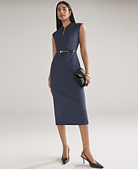 A woman wearing a sleeveless navy blue sheath dress, a thin belt, and pointed-toe heels stands against a plain, light gray background. carousel Product Image 3