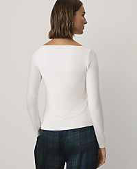 A woman wearing a white long-sleeved top and blue plaid trousers stands against a plain light gray background. carousel Product Image 2