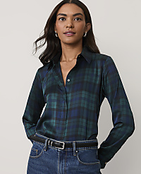 A woman wearing a dark green plaid button-down shirt and blue jeans stands against a plain, light-colored background. carousel Product Image 1