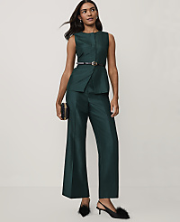 A woman wearing a dark green sleeveless suit and black heels stands against a plain white background. carousel Product Image 1