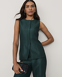 A woman wearing a dark green sleeveless suit and holding a black sequined clutch stands against a plain light gray background. carousel Product Image 1