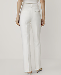 A person stands facing away from the camera wearing white trousers and heels against a plain white background. carousel Product Image 3