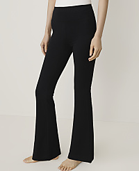 A person wearing black flared trousers and a white top stands against a plain white background. carousel Product Image 1
