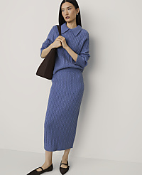 A woman wearing a blue cable-knit sweater and matching skirt stands against a plain white background. carousel Product Image 1