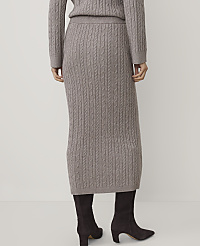 A person stands with their back to the camera wearing a taupe cable-knit sweater and matching skirt with dark brown boots against a plain white background. carousel Product Image 3