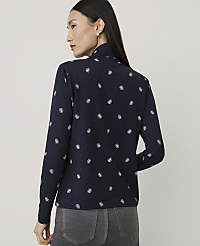 A woman wearing a navy blue patterned long-sleeve shirt and grey pants stands against a plain light grey background. carousel Product Image 2