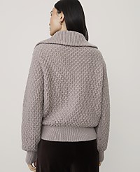 A woman wearing a textured taupe sweater and dark brown trousers stands against a plain light gray background. carousel Product Image 2