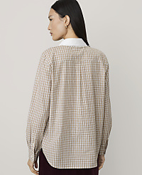 A woman wearing a tan checkered shirt with a white collar stands against a plain, light-colored background. carousel Product Image 2