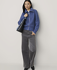 A woman wearing a blue textured zip-up sweater and grey wide-leg trousers stands against a plain white background. carousel Product Image 3