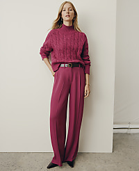 A woman wearing a magenta cable-knit sweater and matching wide-leg trousers stands against a plain white wall. carousel Product Image 4