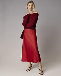 A blonde woman wearing a burgundy off-the-shoulder sweater and a red satin skirt stands against a plain grey background. carousel Product Image 4