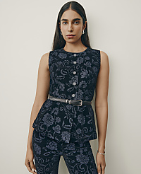 A woman wearing a dark blue floral patterned sleeveless top and matching pants stands against a plain, light-colored wall. carousel Product Image 5