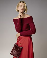A blonde woman wearing a burgundy off-the-shoulder sweater and a red satin skirt stands against a plain grey background. carousel Product Image 3