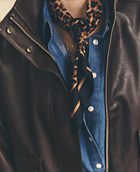 A leopard-print scarf and blue button-down shirt are layered under a dark brown leather jacket. carousel Product Image 3