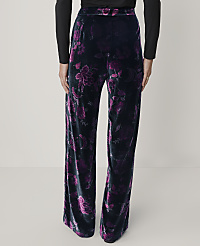 A person wears black long-sleeved top and wide-leg black velvet pants with a purple floral pattern against a plain light gray background. carousel Product Image 3
