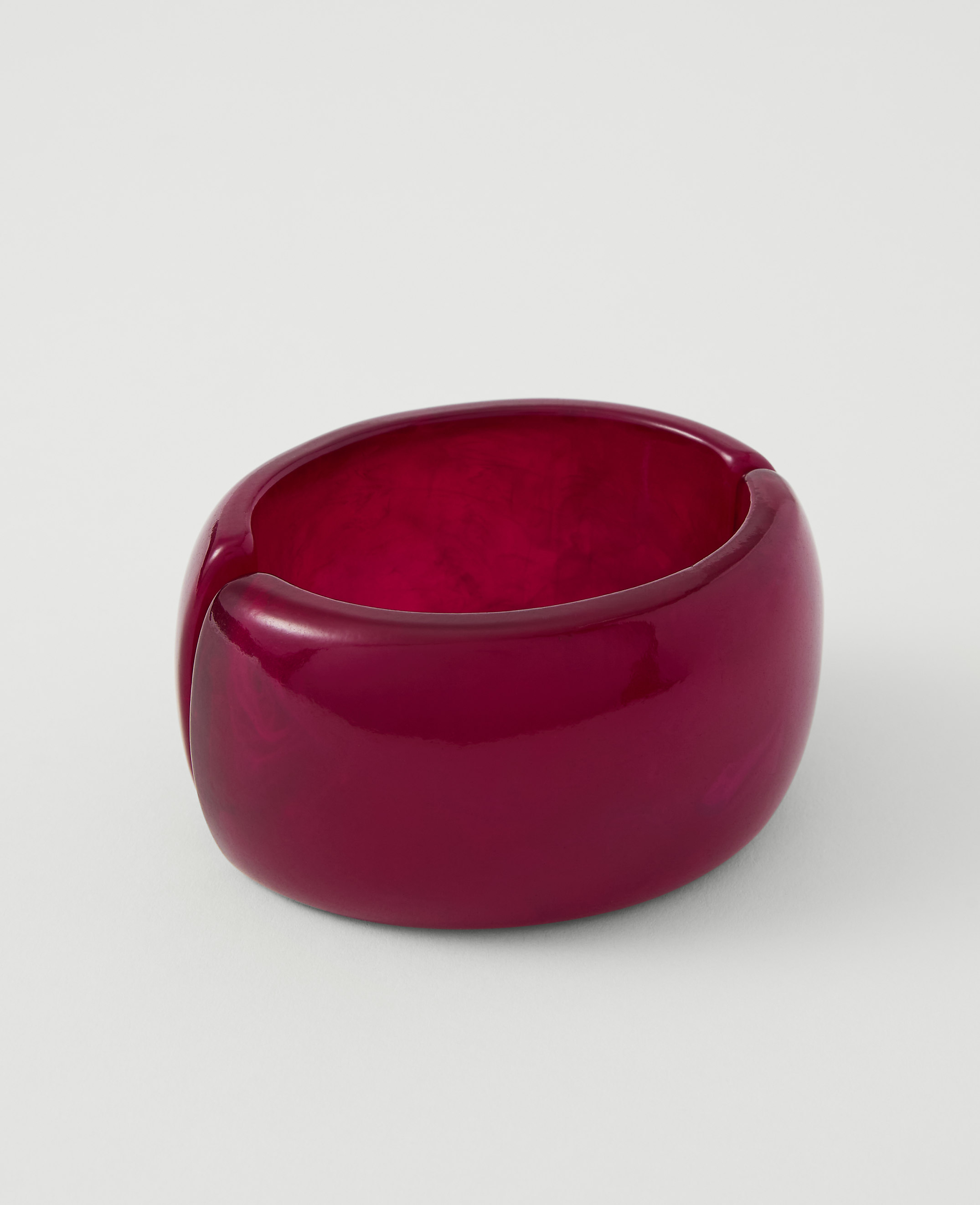 A glossy, deep red, chunky bracelet rests on a plain white background.