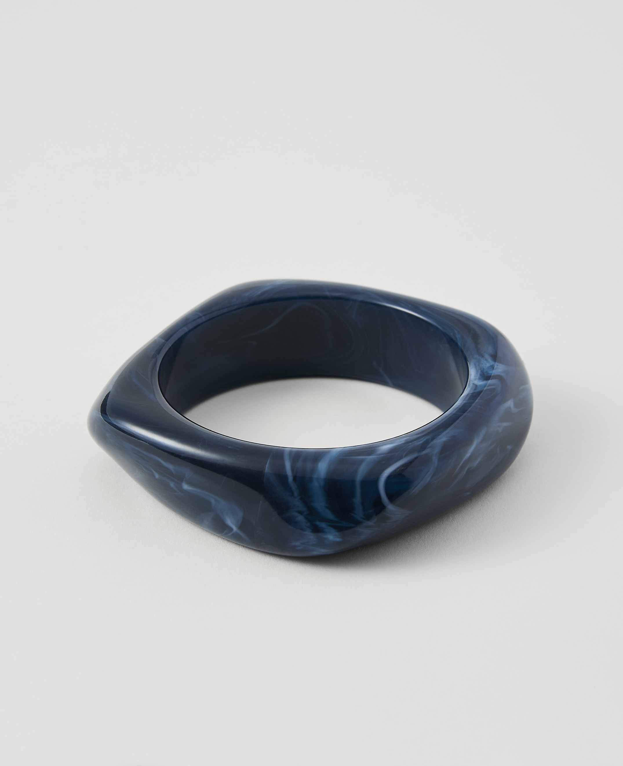 A dark blue, marbled bangle rests on a plain white background.