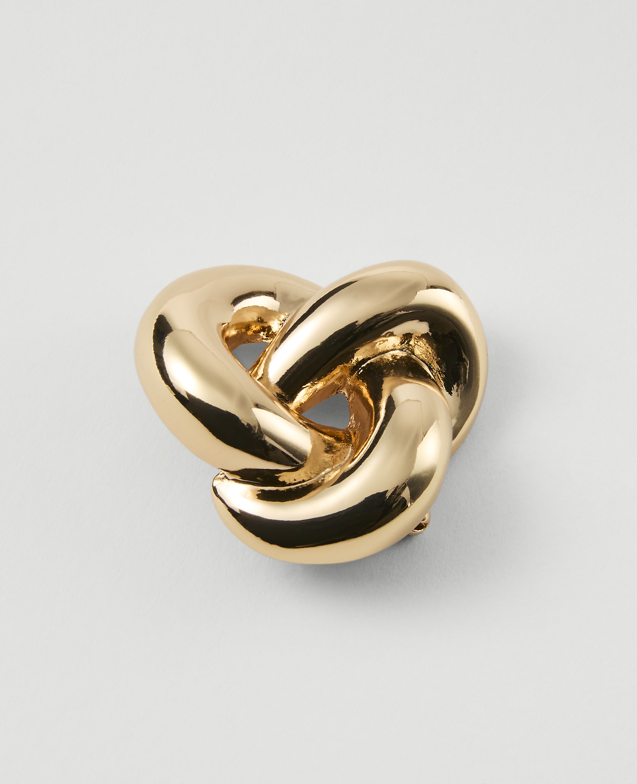 A shiny gold knot rests on a plain white background.